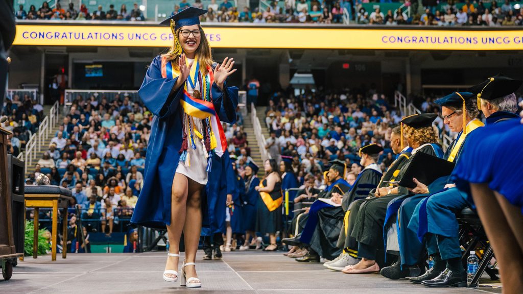 A UNC Greensboro graduate walks the stage at the May 2025 commencement.