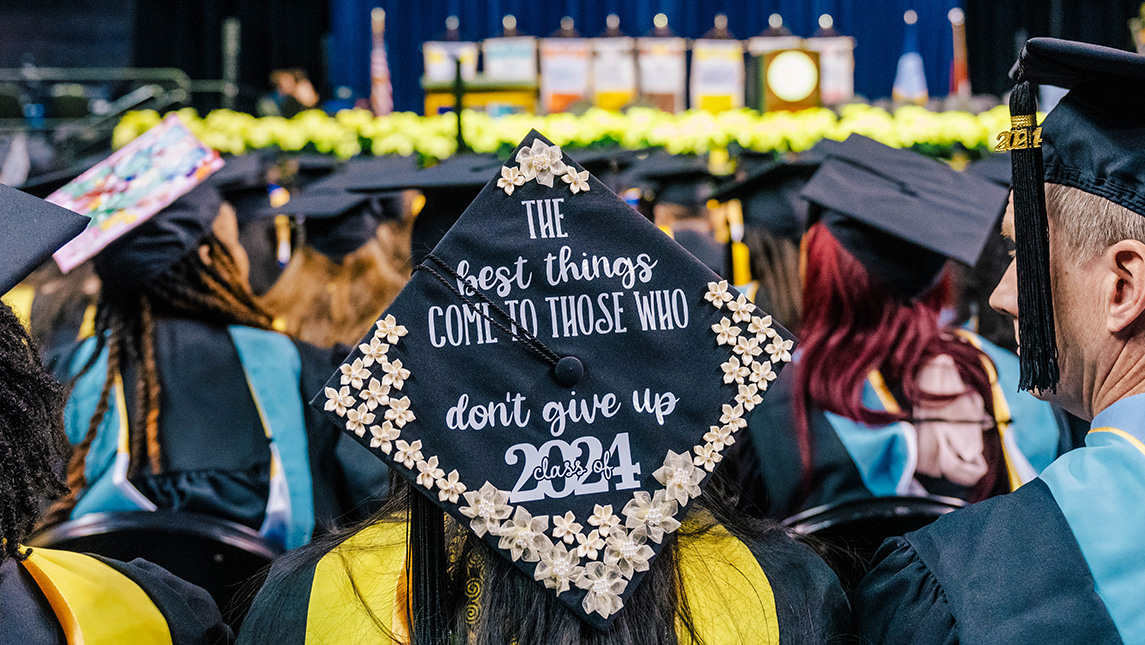 Image of a decorated UNCG Mortarboard reading the best things come to those who don't give up. Class of 2024.